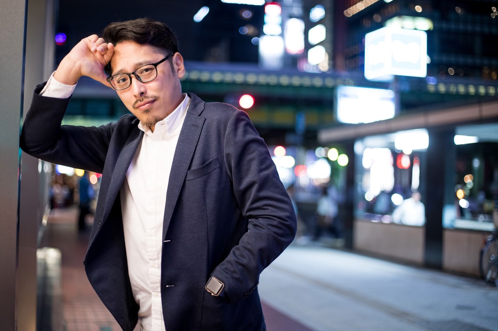 夜の街でドヤ顔をする眼鏡をかけたスーツ姿の男性会社員［モデル：ゆうせい］