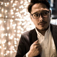 式の二次会から参加するスーツ姿の眼鏡男性の写真