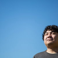 青空を見上げる疲れた表情で目を閉じる男性の顔の写真