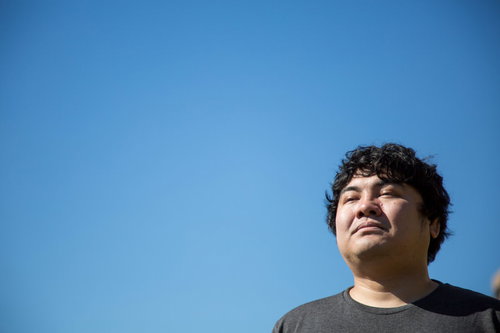 青空を見上げる疲れた表情で目を閉じる男性の顔