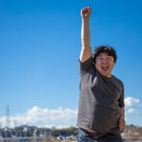 やったぜ！ひゃっほー青空の下でガッツポーズを決める男性の写真