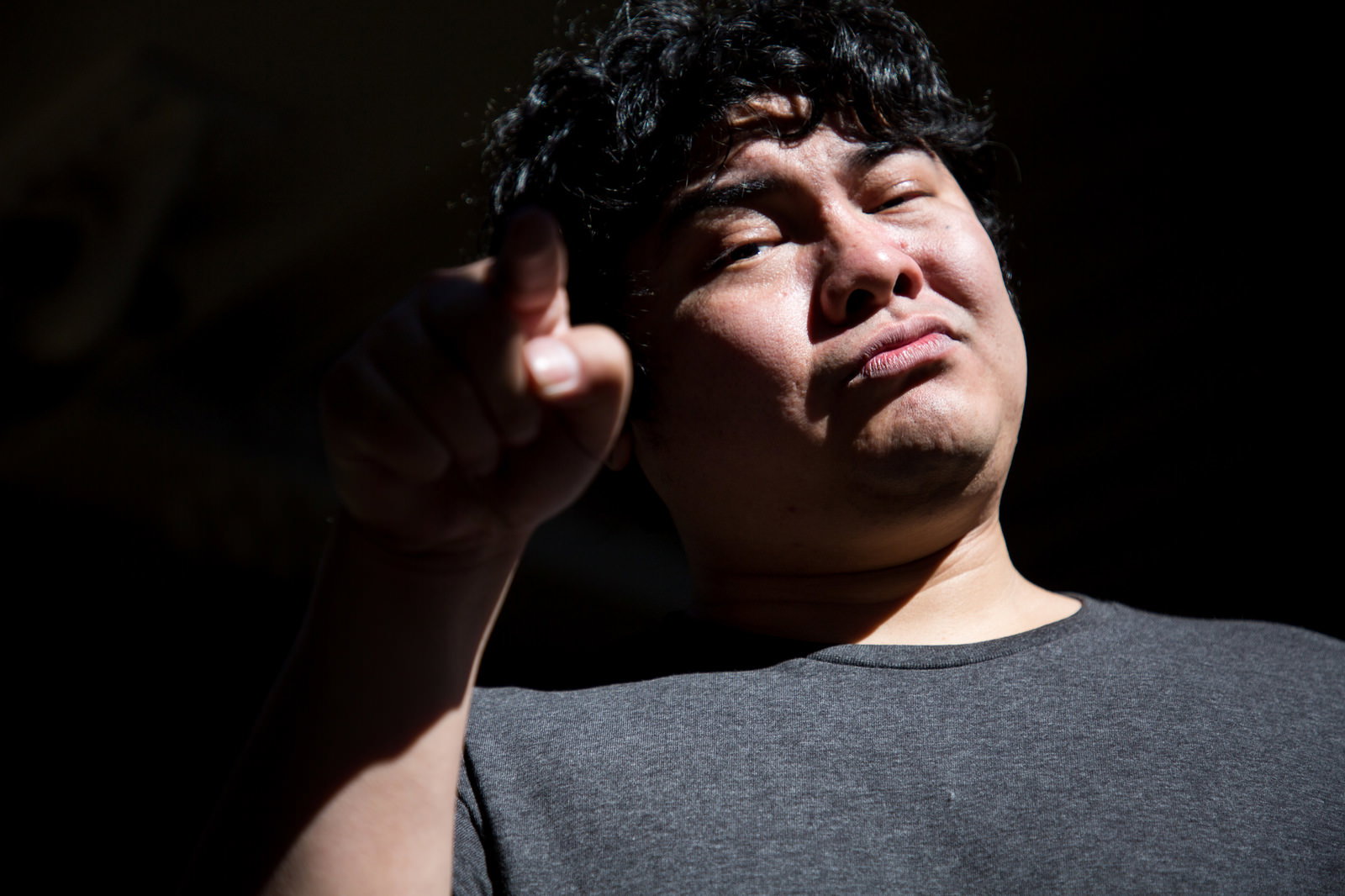 指を立てて怒りの表情を見せるふてくされた肥満の男性［モデル：段田隼人］