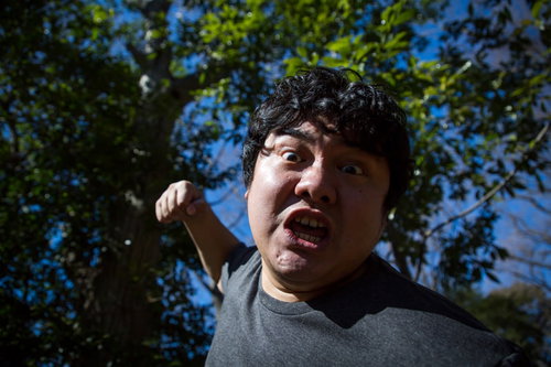 青空を背景に拳を繰り出すパンチシーンの男性