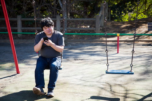 本日の営業は終了しました...っと、公園のブランコでスマホを見る男性