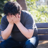 ひとりベンチで項垂れる男性のストレスと悩みの写真