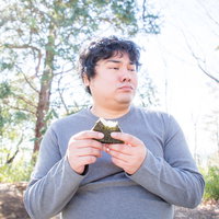 食事中に話しかけるのやめてもらえますか、おにぎりを持つ男性の写真