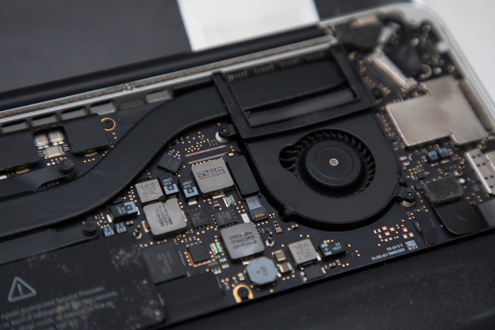 ノートパソコンの内部構造を映した写真。マザーボード上の精密な電子部品と冷却ファンが見える