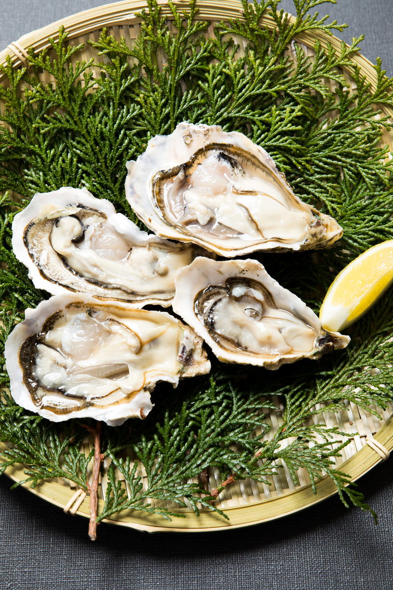 檜葉のザルに盛り付けされた4個の恵比須かきとレモン