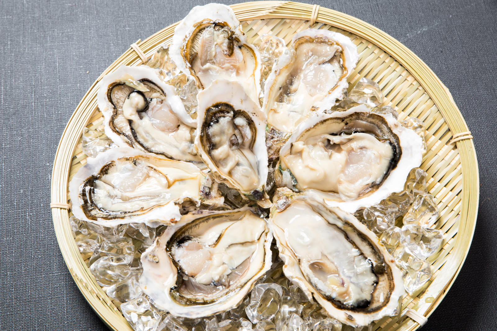 竹ざるの上に盛り付けられた6個の新鮮な恵比須牡蠣