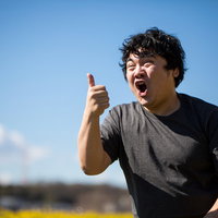 右手でサムズアップする若い男性の写真