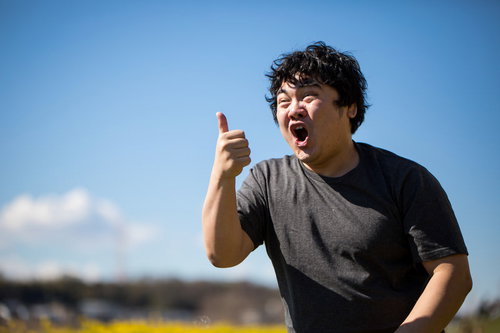 右手でサムズアップする若い男性