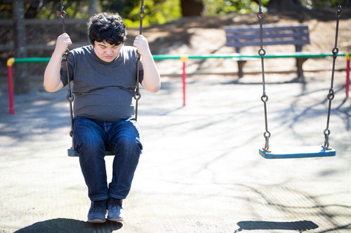 公園のブランコで一人うつむく男性