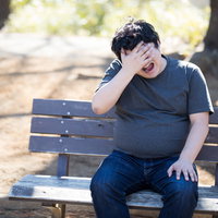 公園のベンチで頭を抱えて絶望する男性の写真