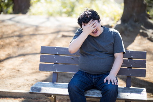 公園のベンチで頭を抱えて絶望する男性