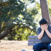 公園のベンチで悩みを抱えて泣く男性、メンタルヘルスの写真