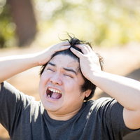 公園のブランコでスマホを見て絶望する男性の写真