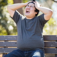 コードレビューばかりで自分の仕事がすすまない...ベンチで頭を抱える男性の写真