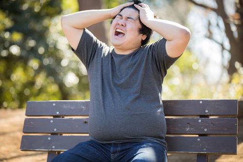 コードレビューばかりで自分の仕事がすすまない...ベンチで頭を抱える男性