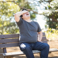 顔出しNGのメタボ男子、公園のベンチで頭を抱えるの写真