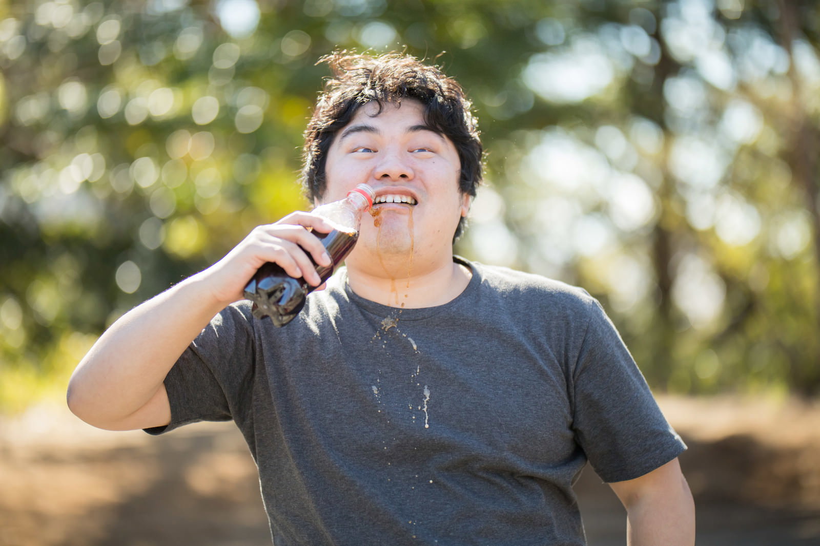 マイクを持ちコーラをがぶ飲みする男性［モデル：段田隼人］