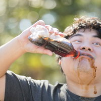 ペットボトルのコーラをがぶ飲みする男子の水分補給の写真