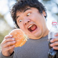 大好物のハンバーガーとコーラを持つ男性の食べる様子の写真