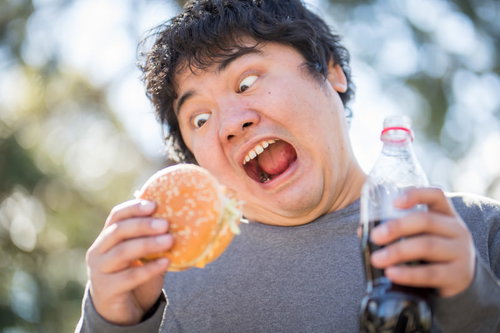 大好物のハンバーガーとコーラを持つ男性の食べる様子