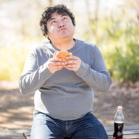 健康診断で要検査が出たけど、ハンバーガーとコーラがうめぇ男性の写真