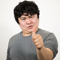 グレーシャツを着た男性のサムズアップポーズの写真