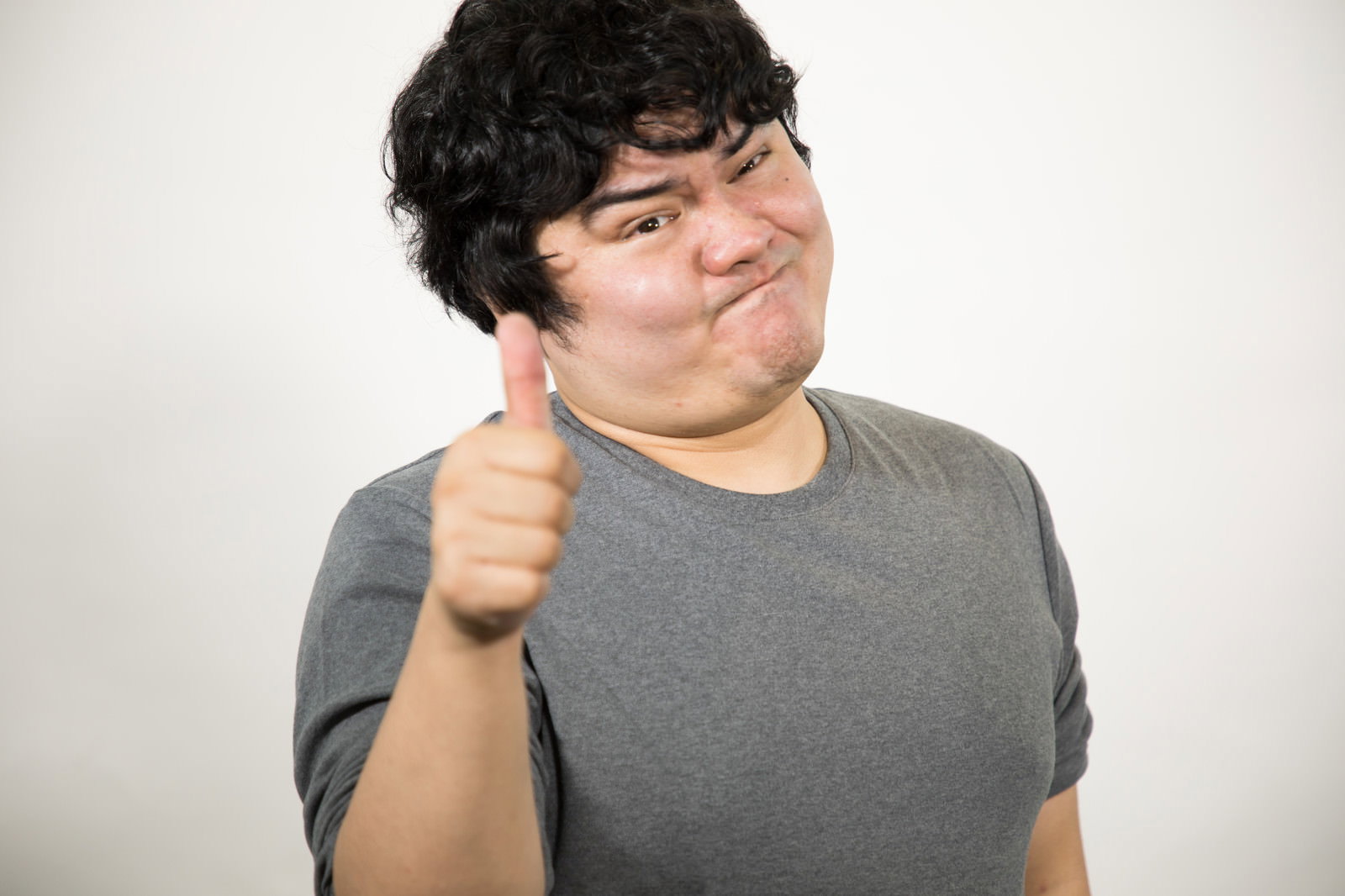 グレーTシャツの男性が右手親指を立てて満足げな表情でいいねポーズをしている［モデル：段田隼人］