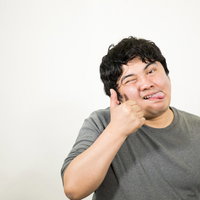舌を出してテヘペロをする灰色Tシャツの男性のポーズの写真