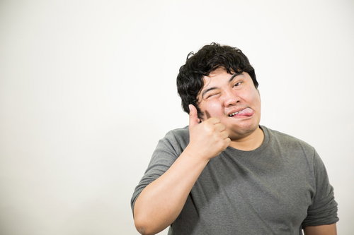 舌を出してテヘペロをする灰色Tシャツの男性のポーズ