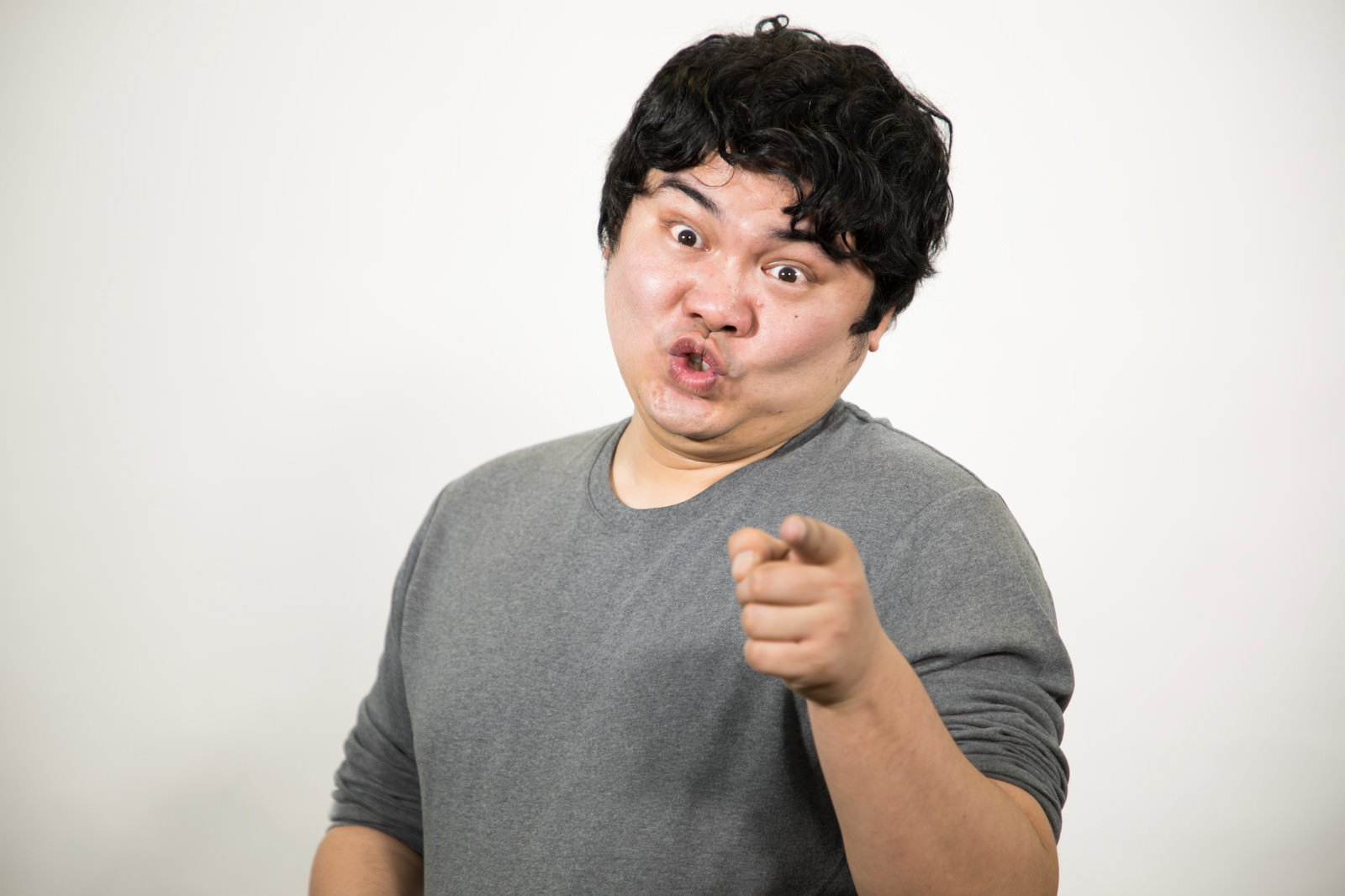 指を突き出して驚く男性［モデル：段田隼人］