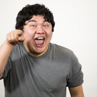 指差しして笑顔の男性ポートレート、灰色Tシャツ姿の写真