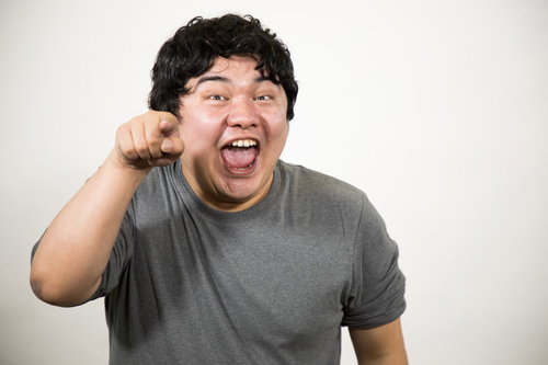 指差しして笑顔の男性ポートレート、灰色Tシャツ姿