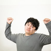 クイズに正解して両手をあげる男性の写真