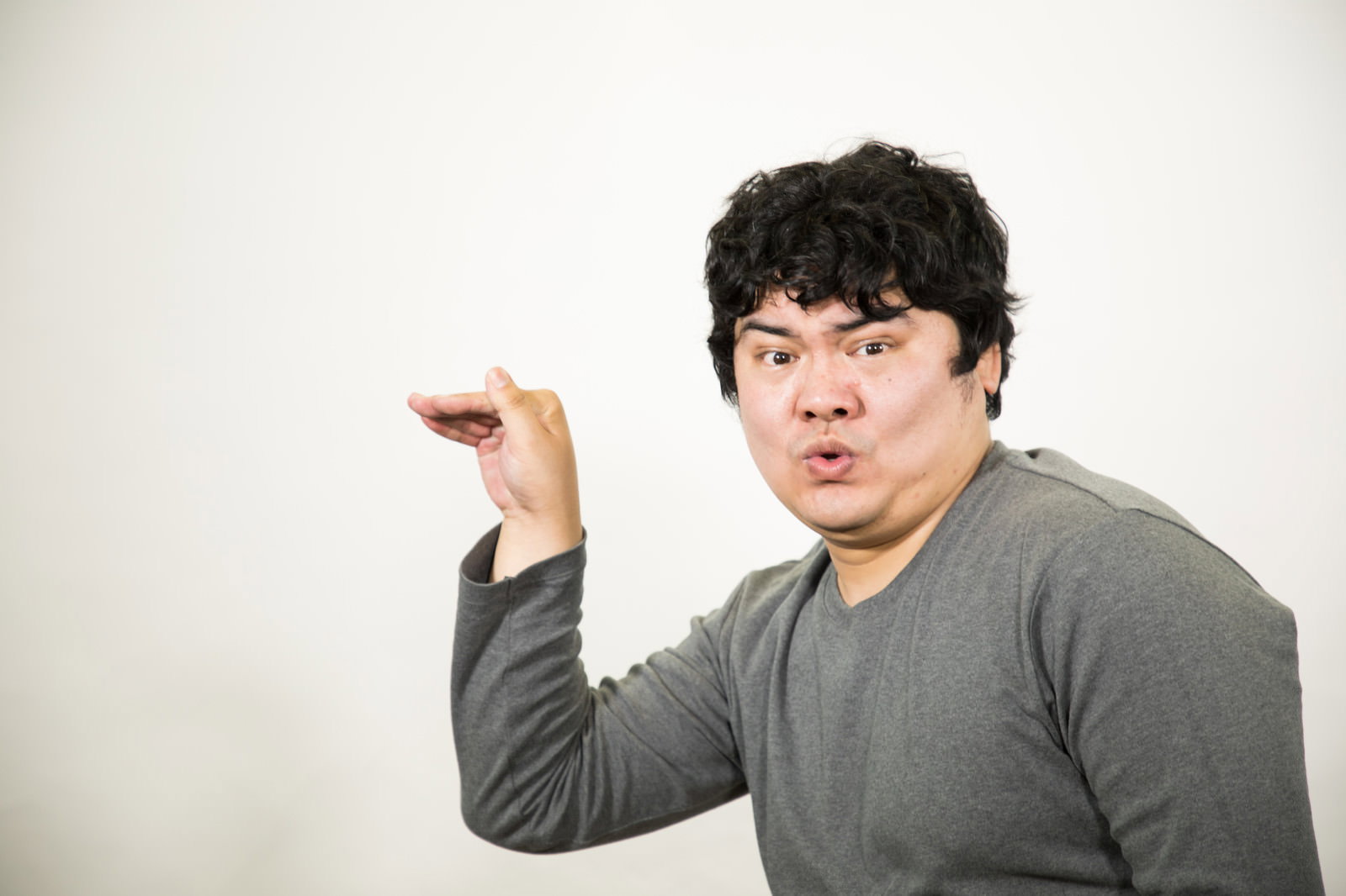 A man in gray clothes making numeric hand gestures