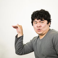 指で2と3どちらなのかよくわからない数字を作る男性の写真