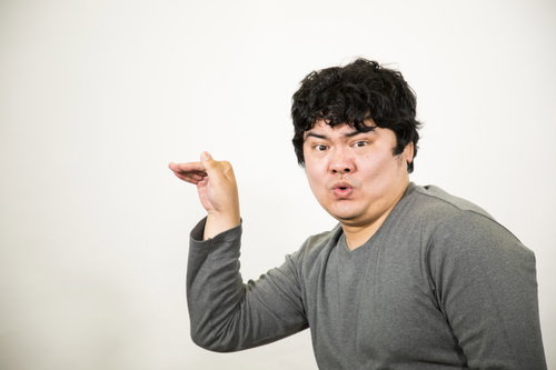 指で2と3どちらなのかよくわからない数字を作る男性