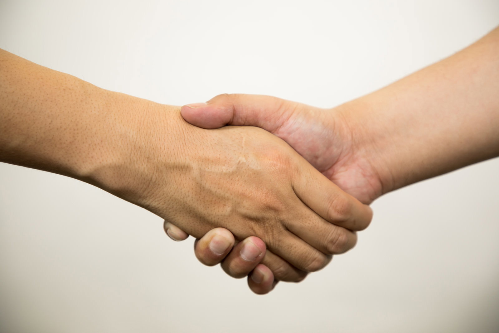 白い背景の前で男性二人が握手している