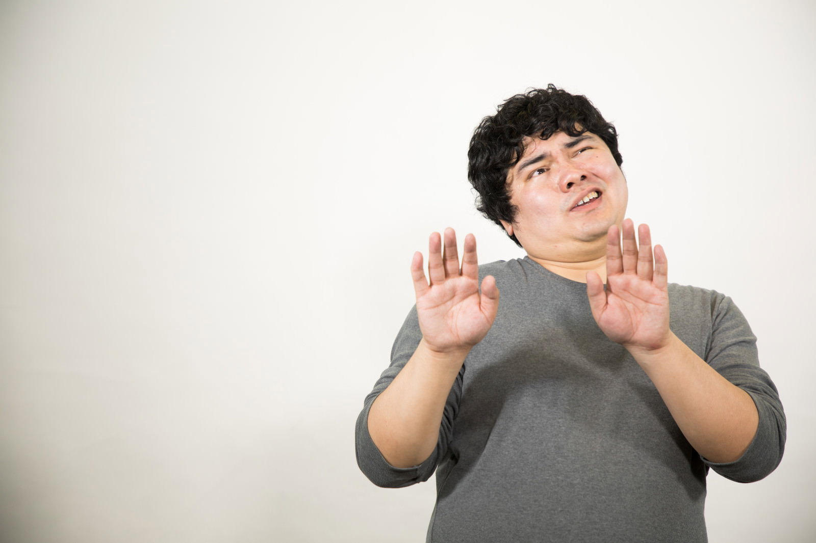 両手のひらを前に向けて拒否するポーズの男性［モデル：段田隼人］
