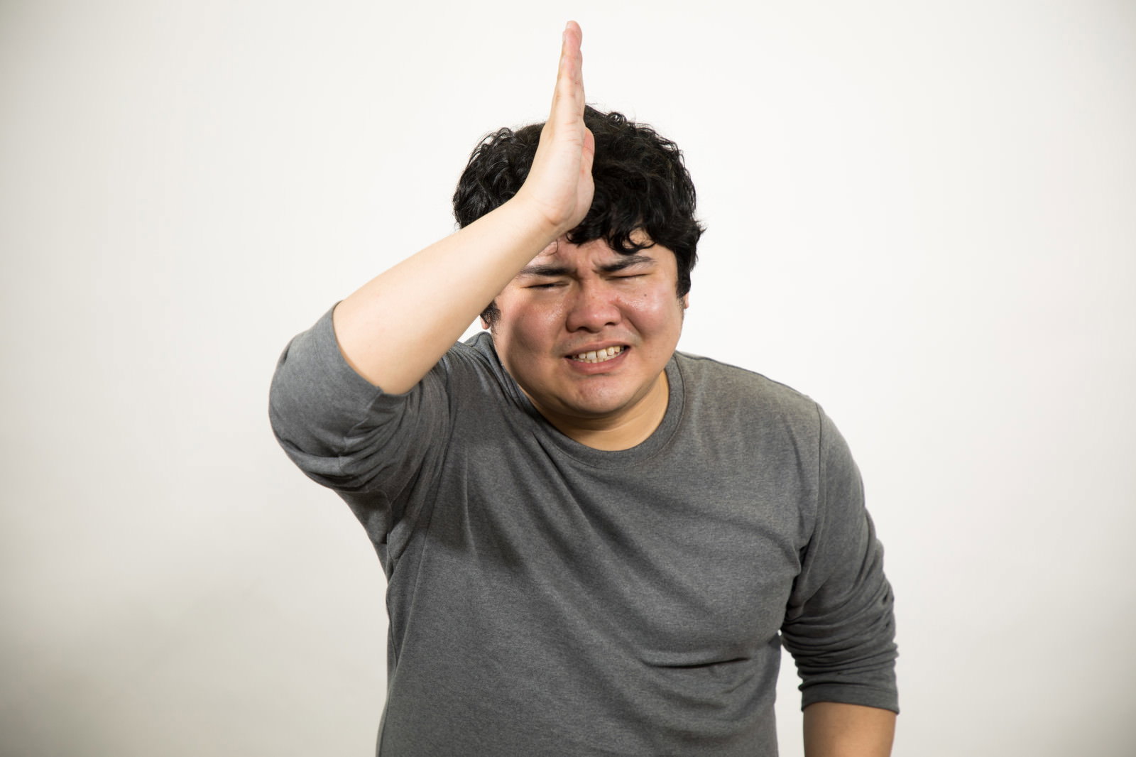 頭を下げて謝りながらお願いするポーズの男性［モデル：段田隼人］