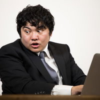 仕様書の内容に驚く男性エンジニアの驚いた表情の写真