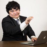 ドヤ顔でタイピングするビジネスマンの写真