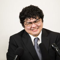 厳しい質問に苦笑いする会社役員の記者会見の写真