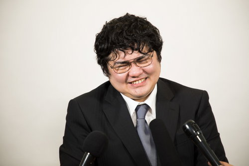 厳しい質問に苦笑いする会社役員の記者会見