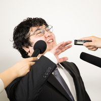 複数のマイクを向けられ執拗な囲み取材を受ける男性の写真