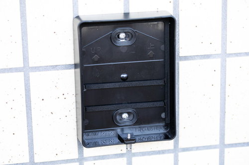 玄関の白いタイル壁に残されたインターホンの取り外され跡