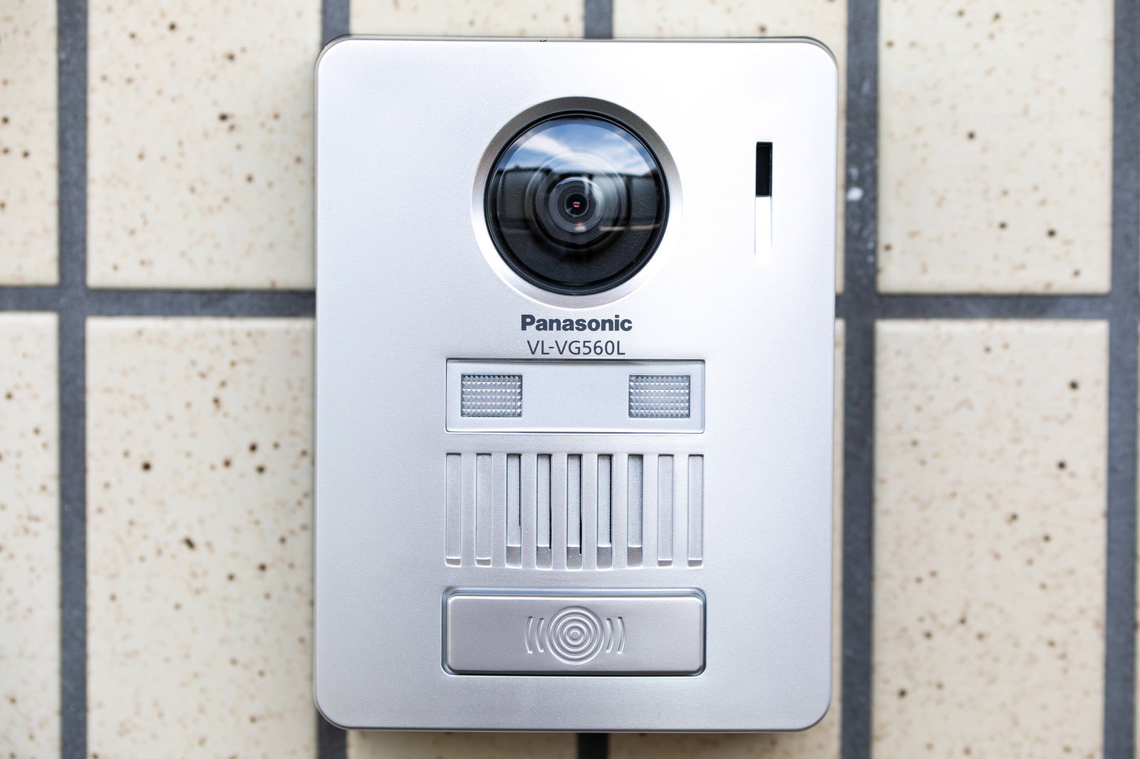 白いタイル壁に取り付けられたカメラ付きインターホン