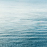 青から水色へのグラデーションが広がる穏やかな海の水面の写真